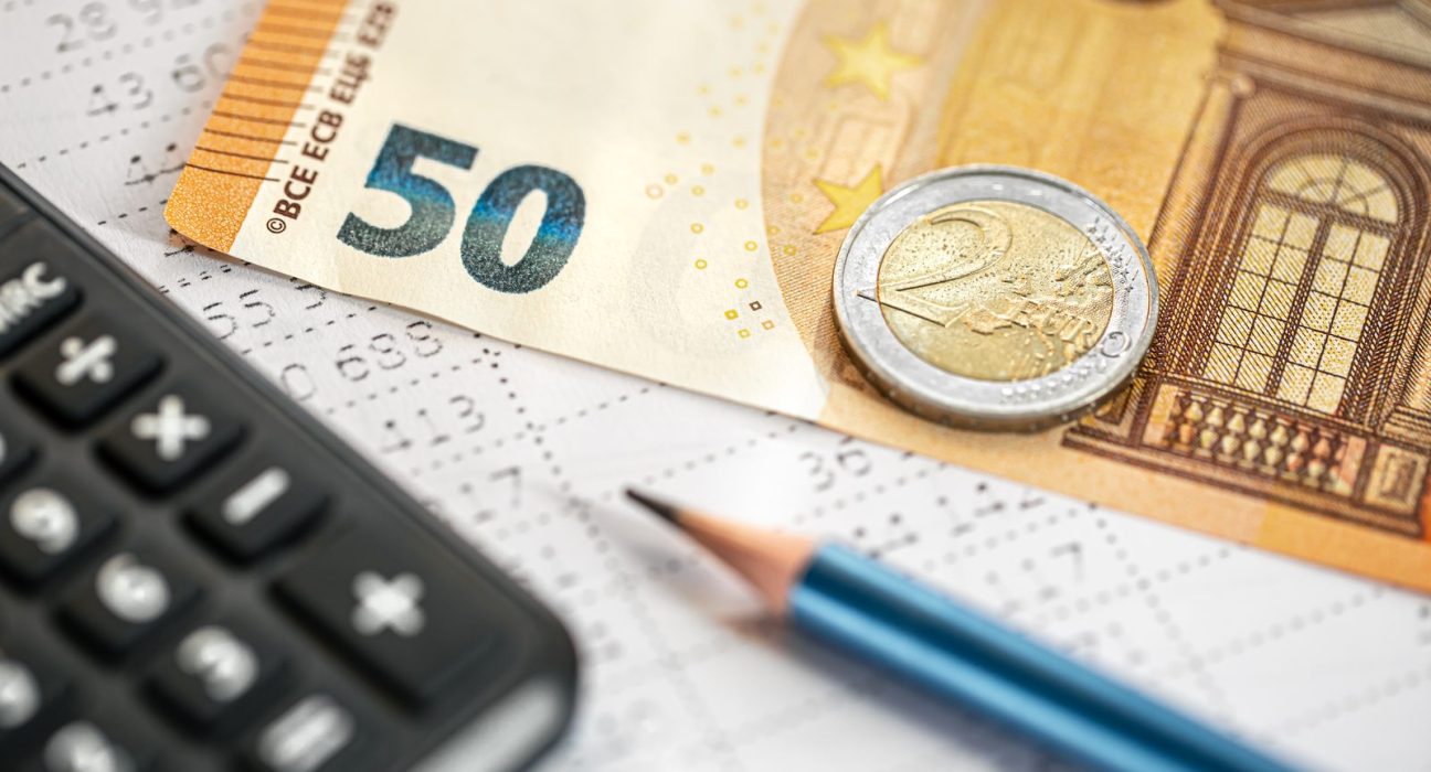 Banknot 50 euro, moneta, kalkulator i ołówek