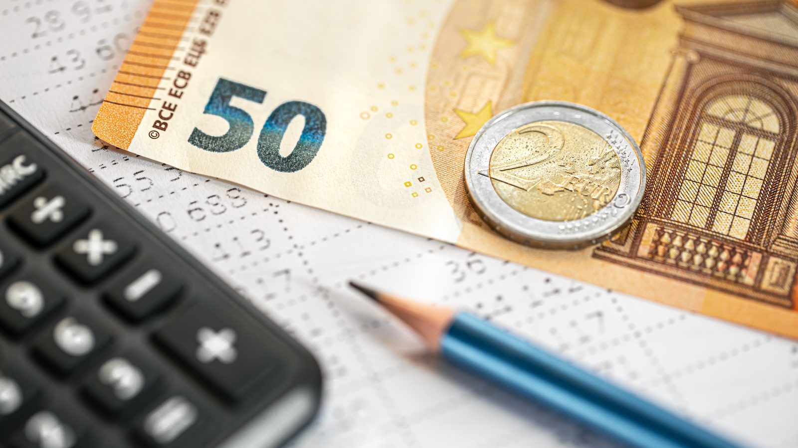 Banknot 50 euro, moneta, kalkulator i ołówek